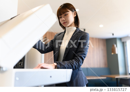 オフィスで複合機を操作する若い女性ビジネスパーソン 133815727