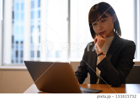 ノートパソコンに向かい集中するスーツ姿の若い日本人女性ビジネスパーソン ノートパソコンに向かい集中するスーツ姿の若い日本人女性ビジネスパーソン 133815732