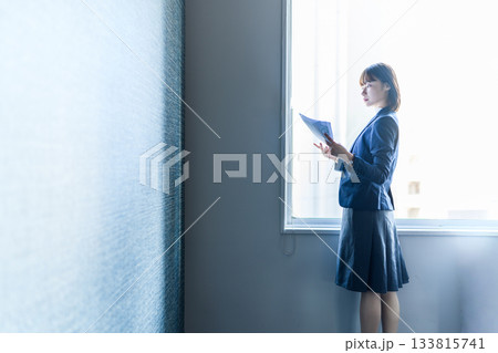 窓際で書類を読む若いビジネスウーマン 133815741