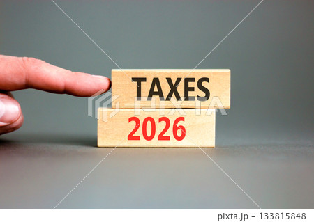Taxes 2026 new year symbol. Concept words Taxes 2026 on beautiful wooden blocks. Beautiful grey paper background. Businessman's hand. Business and taxes 2026 new year concept. Copy space. 133815848