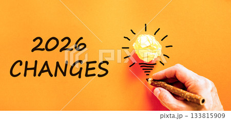 2026 Changes symbol. Concept words 2026 Changes on beautiful orange paper. Beautiful orange paper background. Light bulb icon. Businessman's hand with pen. Business and 2026 changes concept Copy space 133815909