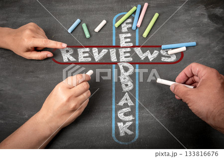 Feedback and Reviews Concept Written with Chalk on Blackboard by Two People 133816676