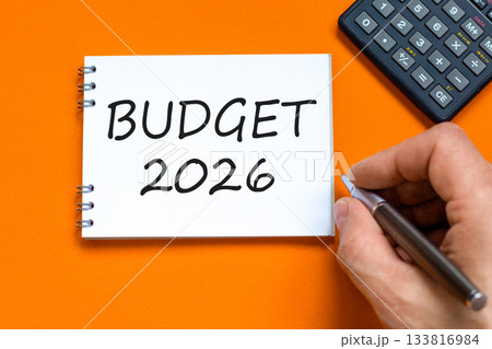 Budget 2026 symbol. Concept words Budget 2026 on beautiful white note. Black calculator. Beautiful orange paper background. Businessman's hand. Business and budget 2026 concept. Copy space. 133816984