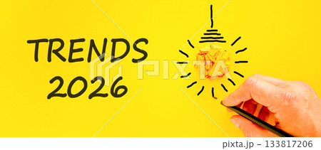 Trends 2026 new year symbol. Concept words Trends 2026 on beautiful yellow paper. Beautiful orange paper background. Businessman's hand with pen. Business Trends 2026 new year concept. Copy space. Trends 2026 new year symbol. Concept words Trends 2026 on beautiful yellow paper. Beautiful orange paper background. Businessman's hand with pen. Business Trends 2026 new year concept. Copy space. 133817206