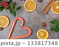 Christmas composition. Christmas candy canes with branches of holly, anis stars, cinnamon sticks, oranges. High quality photo 133817348
