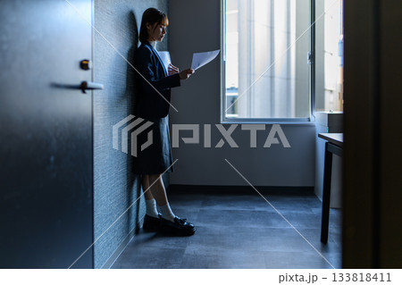 オフィスビル廊下で書類を読む若い女性会社員 133818411