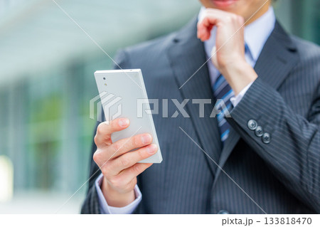 オフィスでスマホを操作する若いビジネスマンの手元 オフィスでスマホを操作する若いビジネスマンの手元 133818470