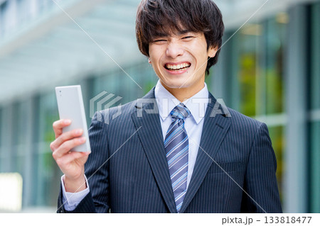 スマートフォンを操作する若いビジネスマン スマートフォンを操作する若いビジネスマン 133818477