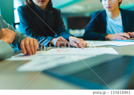 会議で資料を指差して説明するビジネスパーソンたち 133818961