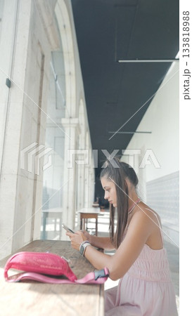 A young woman is engaged with her smartphone while sitting in a modern, stylish space A young woman is engaged with her smartphone while sitting in a modern, stylish space 133818988