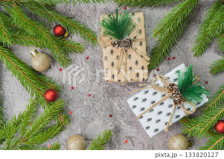 Christmas composition. Gift boxes, fir tree branches, red and gold decorations on grey background. High quality photo 133820127