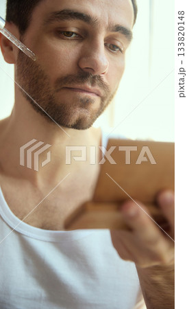 Man applying facial serum with dropper during mindful skincare moment 133820148