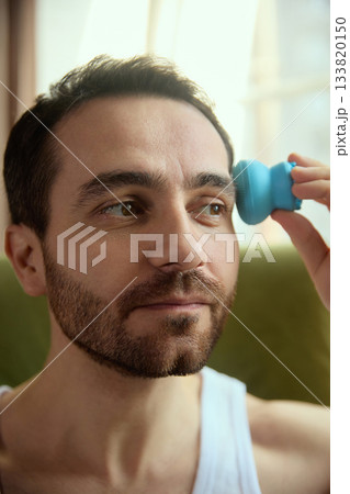 Man massaging facial area with compact electronic skincare device Man massaging facial area with compact electronic skincare device 133820150