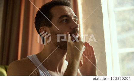 Man applying facial cream after basic skincare routine. 133820204