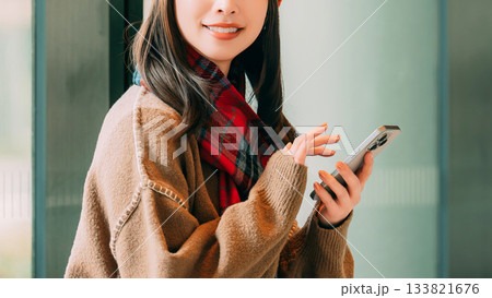 冬の街角でスマートフォンを使う笑顔の女性 冬の街角でスマートフォンを使う笑顔の女性 133821676