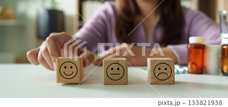 Emotional Expression. Woman selecting wooden blocks with different facial expressions. Emotional Expression. Woman selecting wooden blocks with different facial expressions. 133821938