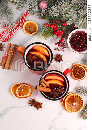 Mulled wine with spices, star anise, cranberry, orange, apple and cinnamon, a warming winter drink in the cold season, strong alcoholic or non-alcoholic cocktail in iron mugs, a Christmas festive grog 133822347