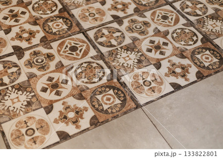 Intricate patterned tiles showcase earthy tones, enhancing the rustic charm of the floor. The bright space feels warm and inviting, perfect for gatherings and relaxation Intricate patterned tiles showcase earthy tones, enhancing the rustic charm of the floor. The bright space feels warm and inviting, perfect for gatherings and relaxation 133822801