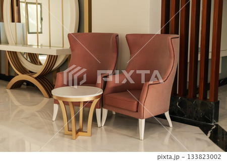 Soft pink armchairs are paired with a round table in a stylish sitting area. The room features sleek lines and a mixture of textures, inviting relaxation and conversation 133823002
