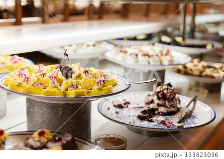 A vibrant dessert buffet features assorted sweets, including cakes and pastries, beautifully arranged on silver platters ready for guests to enjoy at a lively celebration 133823036