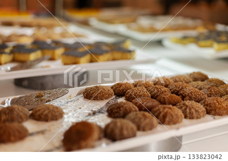 A selection of sweet treats is beautifully arranged on trays for guests to enjoy at a celebration. Different pastries and candies are presented, showcasing variety A selection of sweet treats is beautifully arranged on trays for guests to enjoy at a celebration. Different pastries and candies are presented, showcasing variety 133823042
