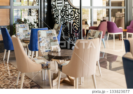 Seating area in a contemporary cafe features colorful chairs and a tastefully designed ambiance. A combination of patterns and textures creates a warm, inviting space for relaxation and socializing Seating area in a contemporary cafe features colorful chairs and a tastefully designed ambiance. A combination of patterns and textures creates a warm, inviting space for relaxation and socializing 133823077