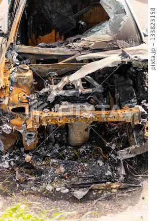 A car that caught fire is now a burnt shell, showing severe damage inside and out. The remnants of the engine and burnt materials are visible in a roadside setting A car that caught fire is now a burnt shell, showing severe damage inside and out. The remnants of the engine and burnt materials are visible in a roadside setting 133823158