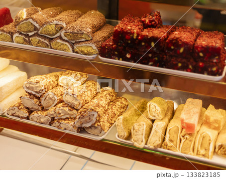 A vibrant display of traditional sweets featuring a variety of textures and colors. The showcase includes rolled confections and cubes, inviting customers to indulge in unique flavors 133823185