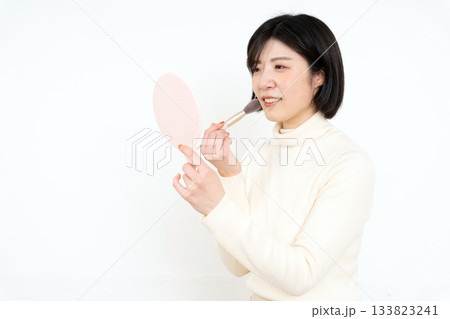 手鏡を持ってお化粧をする笑顔の女性 133823241
