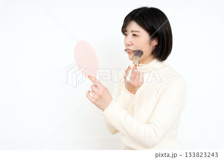 手鏡を持ってお化粧をする笑顔の女性 手鏡を持ってお化粧をする笑顔の女性 133823243