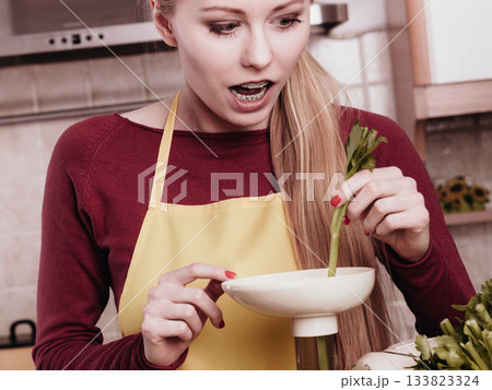 Woman in kitchen making vegetable smoothie juice 133823324