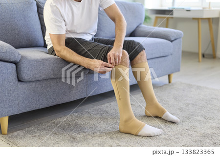 Man using compression stockings for varicose veins, zipping up elastic socks Man using compression stockings for varicose veins, zipping up elastic socks 133823365