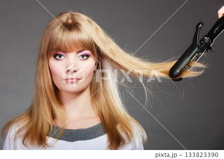 woman making hairstyle with hair iron woman making hairstyle with hair iron 133823390