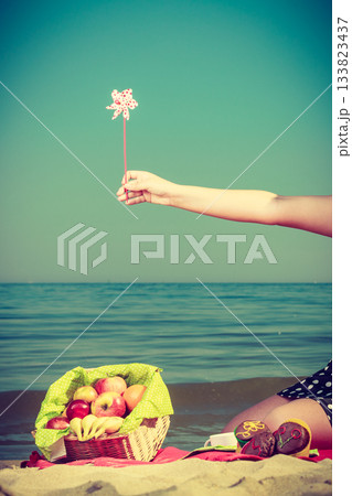Woman hand holding windmill, sea in background 133823437