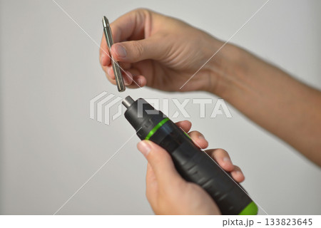 A man changing drill bit in electric screwdriver A man changing drill bit in electric screwdriver 133823645