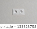 Two white outlets are on a white wall. 133823758