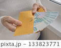 A person holding a gold envelope with a bunch of bills inside 133823771