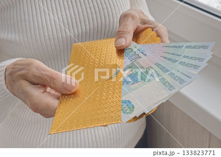 A person holding a gold envelope with a bunch of bills inside A person holding a gold envelope with a bunch of bills inside 133823771