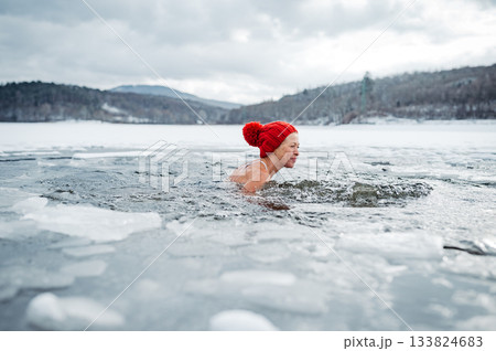 Elderly woman practicing outdoor ice bathing during winter season 133824683
