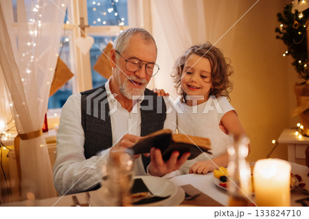 Grandparent reading from bible during Christmas dinner. 133824710