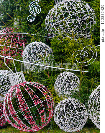 Large outdoor Christmas ornament decorations with lighted wire spheres on evergreen trees Large outdoor Christmas ornament decorations with lighted wire spheres on evergreen trees 133825429