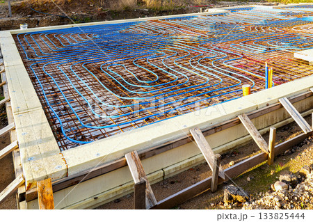 Underfloor heating pipes over reinforced rebar grid before concrete foundation slab pouring Underfloor heating pipes over reinforced rebar grid before concrete foundation slab pouring 133825444
