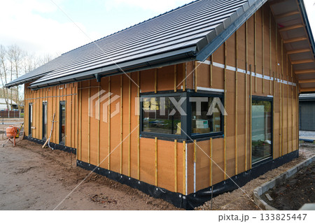 Modern house under construction with wood fiber insulation panels and battens for exterior cladding Modern house under construction with wood fiber insulation panels and battens for exterior cladding 133825447
