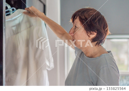 Elderly woman cleaning her home, organizing and tidying up with care in a bright living space. Concept of active aging, independence, daily routine, healthy lifestyle, and maintaining a comfortable 133825564