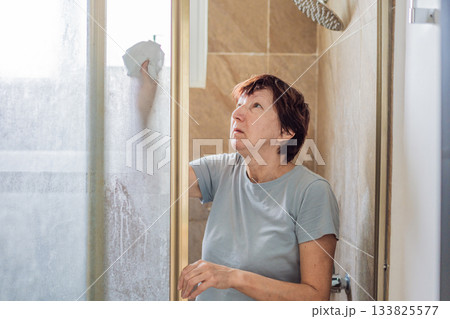 Elderly woman cleaning her home, organizing and tidying up with care in a bright living space. Concept of active aging, independence, daily routine, healthy lifestyle, and maintaining a comfortable 133825577