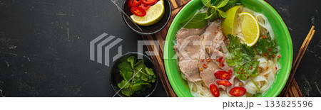 Vietnamese pho bo noodle soup beef lime asian bowl dinner black background wooden cutting board copy space 133825596