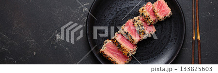 Seared grilled tuna steak tataki slices sesame seeds lemon black plate healthy delicacy space for text Seared grilled tuna steak tataki slices sesame seeds lemon black plate healthy delicacy space for text 133825603