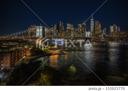 Night view of Brooklyn Bridge and illuminated Manhattan skyline reflected in East River Night view of Brooklyn Bridge and illuminated Manhattan skyline reflected in East River 133825770