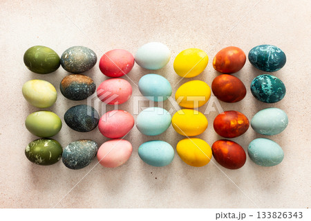 Dozens of beautifully colored Easter eggs in bright shades of green, pink, yellow, blue, and red are arranged in neat rows on a light background, ready for holiday festivities Dozens of beautifully colored Easter eggs in bright shades of green, pink, yellow, blue, and red are arranged in neat rows on a light background, ready for holiday festivities 133826343