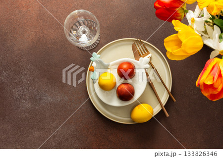 A beautifully arranged Easter table setting showcases a yellow napkin wrapped around a red apple, surrounded by vibrant flowers and a festive bunny decoration A beautifully arranged Easter table setting showcases a yellow napkin wrapped around a red apple, surrounded by vibrant flowers and a festive bunny decoration 133826346